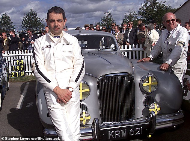 Imagem de Rowan Atkinson em frente a um carro jaguar